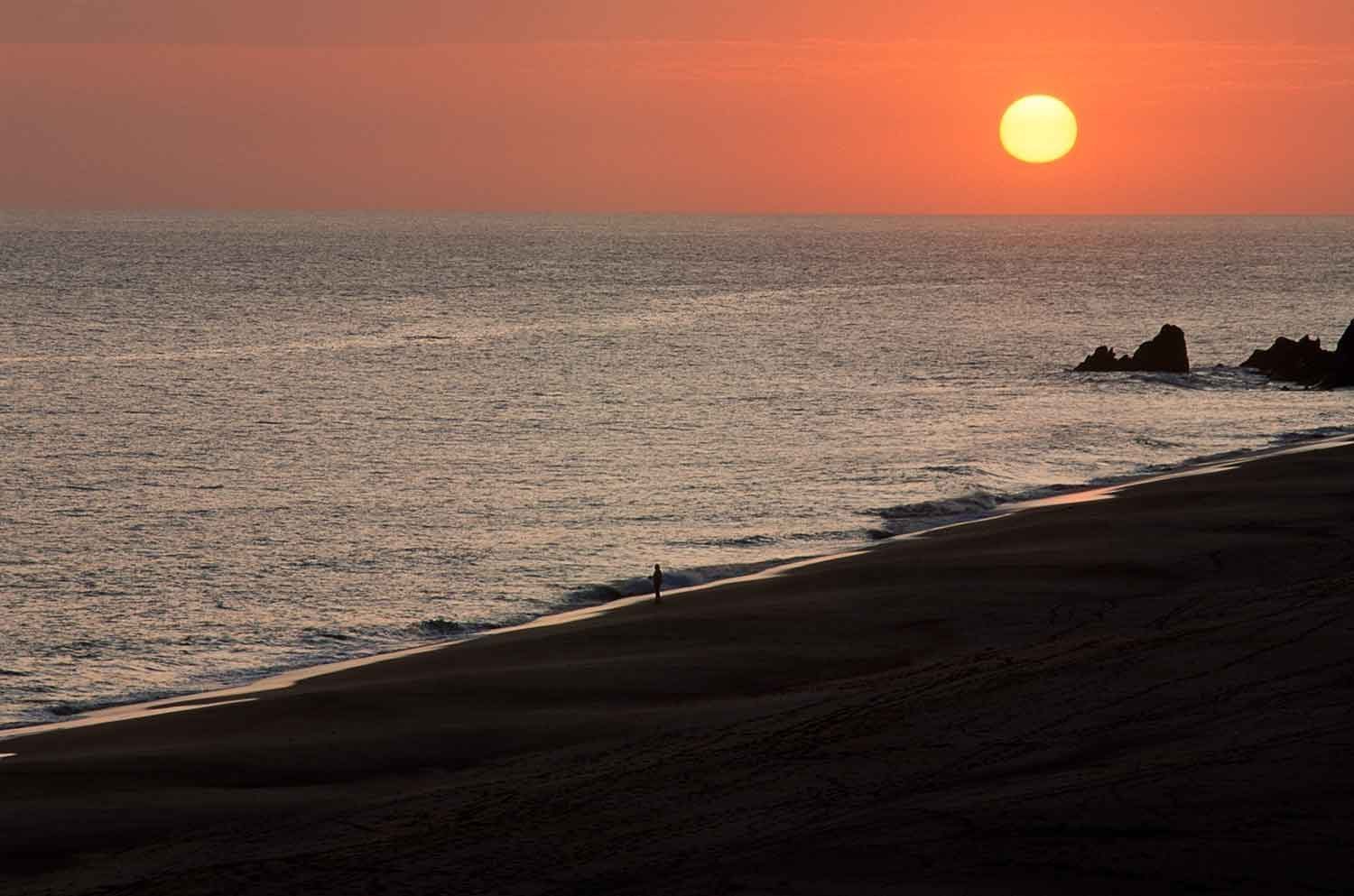 Pacific Ocean sunset from Pedregal Cabo San Lucas with cliffside homes silhouetted against the sky